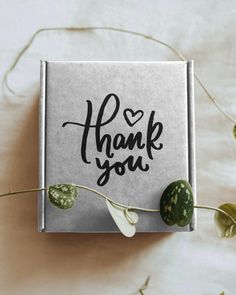 a thank card with the words thank you written on it next to some green leaves