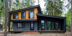 a small house in the woods with lots of windows and wood trimming on it