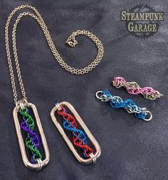 three different colored chainmails are on a black surface and one is attached to a silver chain