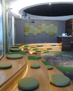 an office with green and yellow seating on the floor, and round wooden tables in the center