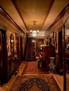 an ornate hallway with stairs and chandelier in the center is lit by lights