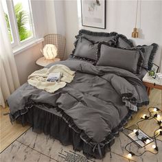 the comforter is made up with ruffles and lights on the floor next to it