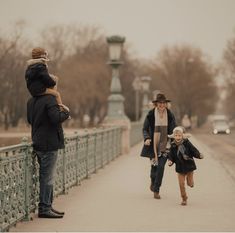 a woman and two children walking across a bridge