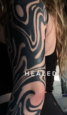 a woman's arm with black and white tattoos on it, that reads healed