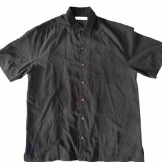 This Tommy Bahama shirt in black is made of 100% silk and features short sleeves with button closure, a collared neckline, and a regular fit. The shirt is perfect for any occasion and can be dressed up or down. The accents include button detailing, making it a versatile piece for any wardrobe. The shirt is a size large and is an all-seasons item that can be worn year-round. The point collar style adds a touch of sophistication to any outfit. This shirt is perfect for any man looking for a stylis Black Short Sleeve Summer Shirt, Black Tops With Buttoned Collared Neckline, Black Collared Top With Button Closure, Black Collared Top With Buttons, Black Tops With Collared Neckline And Buttons, Black Tops With Buttons And Collared Neckline, Black Top With Button Closure And Collared Neckline, Black Shirt With Button Closure For Summer, Black Buttoned Shirt For Summer