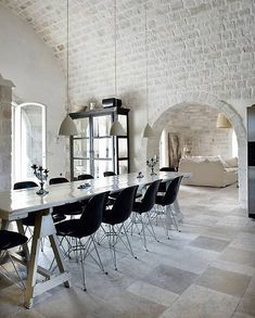 a long table with black chairs in front of a brick wall and arched doorways