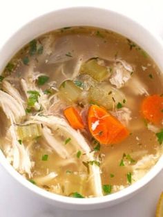 two bowls of chicken soup with carrots, celery and parsley on the side