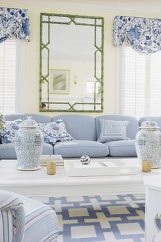 a living room with blue and white decor on the couches, coffee table and mirror