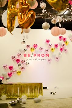 balloons and streamers are hanging from the ceiling in front of a room with white walls