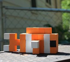 an orange and white block sitting on top of a table next to a building made out of blocks