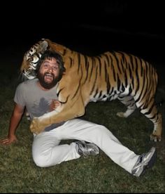 a man laying on the ground with a stuffed tiger on his back in front of him