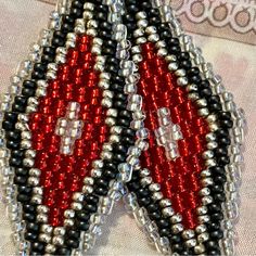 two red and black beaded earrings sitting on top of each other