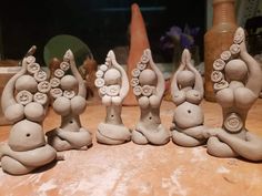 five clay sculptures sitting on top of a wooden table