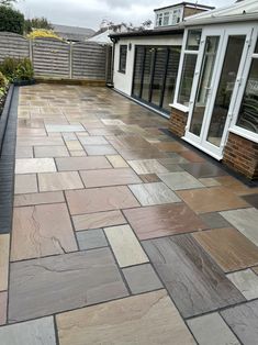 an outdoor patio with stone pavers and sliding glass doors on the side of it