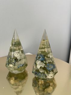 two clear pyramid shaped vases with flowers in them