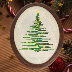 a cross stitch christmas tree ornament on a table