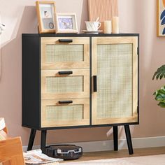 a wooden cabinet with drawers and pictures on top in a room next to a potted plant