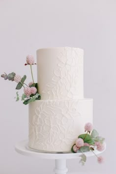 a white wedding cake with pink flowers and greenery