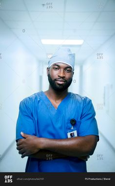 a man in scrubs is standing with his arms crossed and looking at the camera