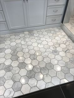 a kitchen with white cabinets and marble flooring on the counter top, along with an area rug that has light colored hexagon tiles