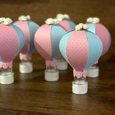 four pink and blue hot air balloons sitting on top of a wooden table