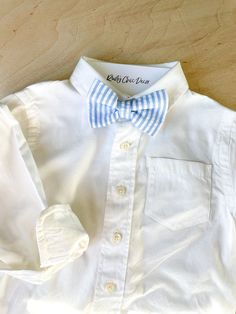 a white shirt with a blue and white striped bow tie is laying on the floor