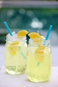 two mason jars filled with lemonade sitting on top of a white table next to each other