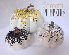 three white pumpkins with black and gold confetti on them, sitting side by side