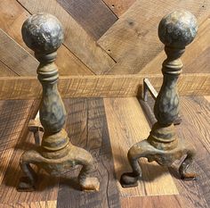 two metal candlesticks sitting on top of a wooden floor