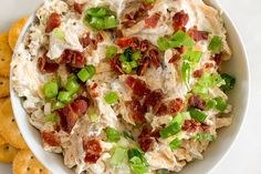 a white bowl filled with chicken salad next to crackers