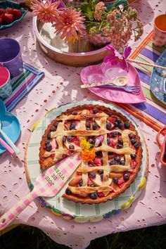 a pie sitting on top of a table covered in plates and bowls filled with fruit