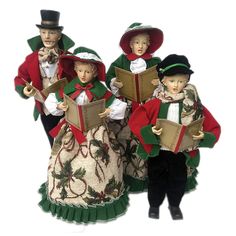 three figurines are dressed in costumes and holding books