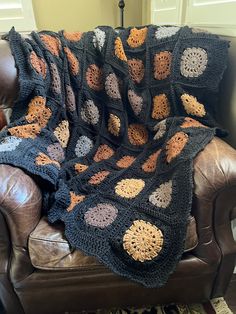 a crocheted blanket sitting on top of a leather chair