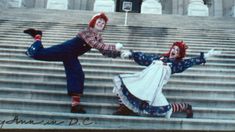 two people dressed as clowns dancing on steps