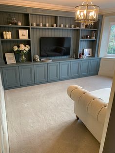 a living room filled with furniture and a flat screen tv sitting on top of a wooden shelf