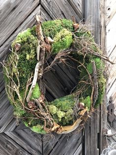 a moss covered wreath hanging on the side of a wooden door