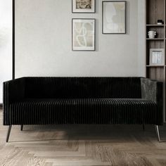 a black couch sitting in front of a book shelf on top of a hard wood floor