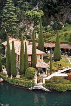 an aerial view of a house with trees on the side and water in the foreground