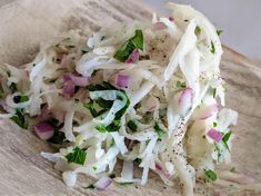 a wooden cutting board topped with coleslaw slaw and chopped green onions on top