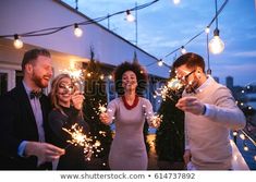 group of friends celebrating with sparklers on rooftop at night