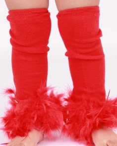 the legs and feet of a child wearing red socks with fluffy feathers on them, against a white background