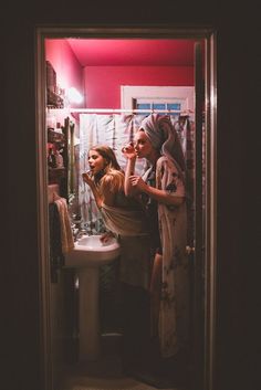 two women standing in front of a bathroom mirror