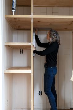 a woman standing on top of a wooden shelf next to shelves filled with books and papers