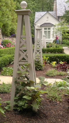 a white clock tower sitting in the middle of a garden