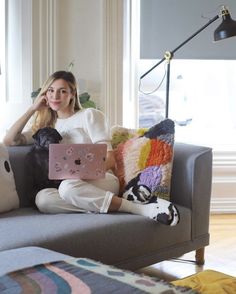 a woman sitting on a couch holding a laptop