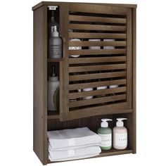 a wooden cabinet with some bottles and soaps on it's shelf next to other bathroom items