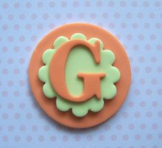 an orange and green cookie with the letter g in it's center on a blue background