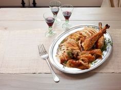 a white plate topped with chicken next to wine glasses