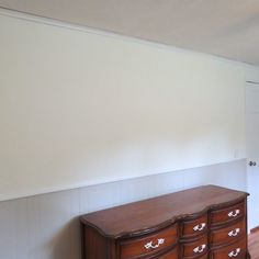 an empty room with white walls and wooden furniture