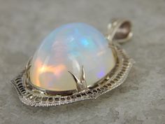 Ethiopian Opal And Filigree White Gold Pendant Of by MSJewelers Formal Ethiopian Opal Cabochon Jewelry, Ethiopian Opal Oval Pendant Jewelry Gift, Fine Jewelry Ethiopian Opal Pendant, Formal Ethiopian Opal Oval Cabochon Jewelry, White Ethiopian Opal Cabochon Jewelry, Hallmarked Ethiopian Opal Pendant Jewelry, Elegant Ethiopian Opal Oval Cabochon Jewelry, White Gold Pendant, Ethiopian Opal Gemstone Jewelry, Round Shape